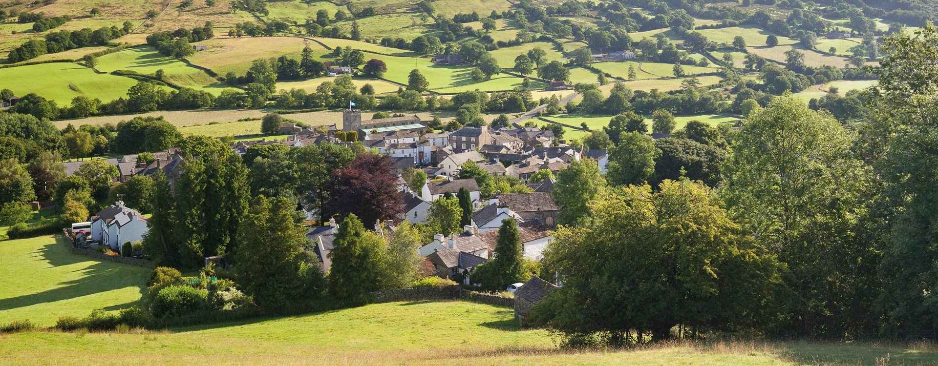 Dent village from the hillside above, with the fields of Dentdale beyond