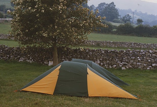 A tent pitched by a drystone wall at High Laning, with the fells behind